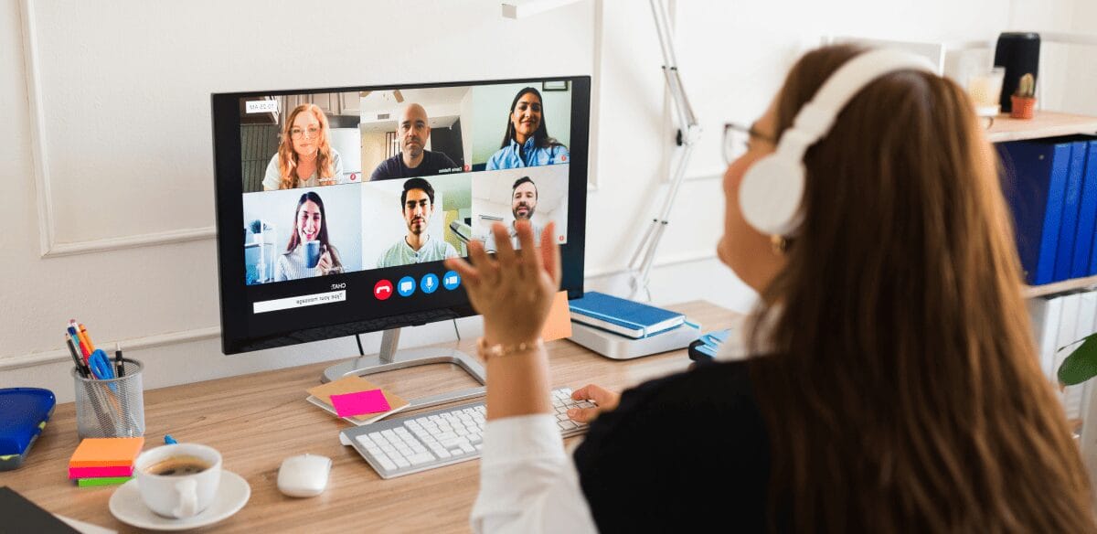 A woman engaged in a video chat on her computer, connecting with others through a virtual meeting.