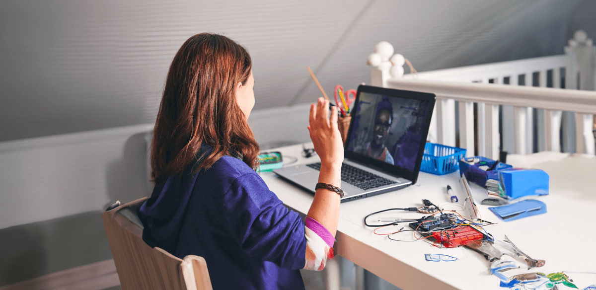 A woman seated at a desk, focused on her laptop, surrounded by a tidy workspace.